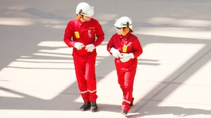 身穿紅色工作服、頭戴白色頭盔和聽力保護裝置行走的男女工人