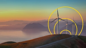 照片：一座山上有三台風力渦輪機，帶有「實現淨零排放」的輪廓圖